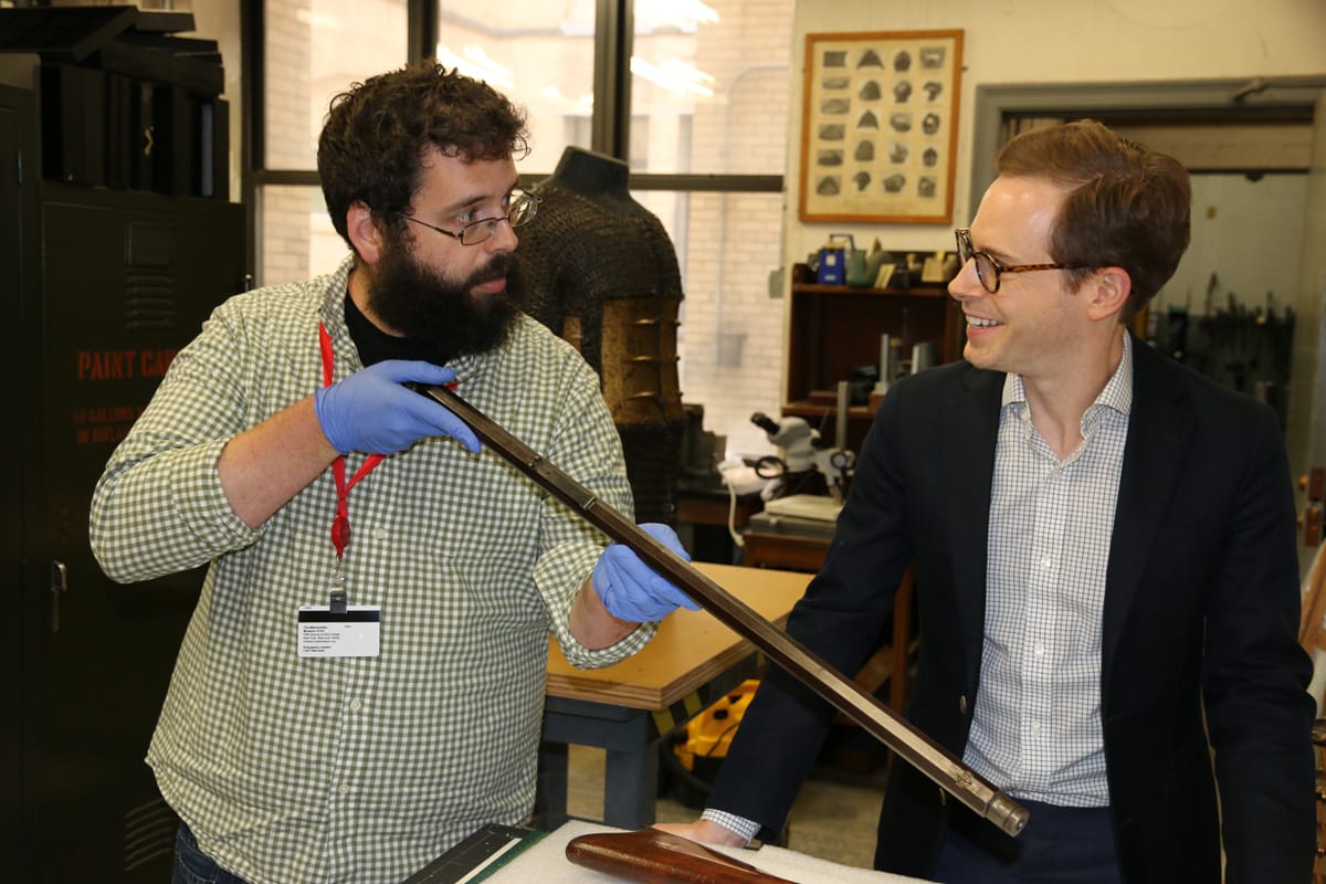 John Byck and his colleague inspecting part of a firearm.