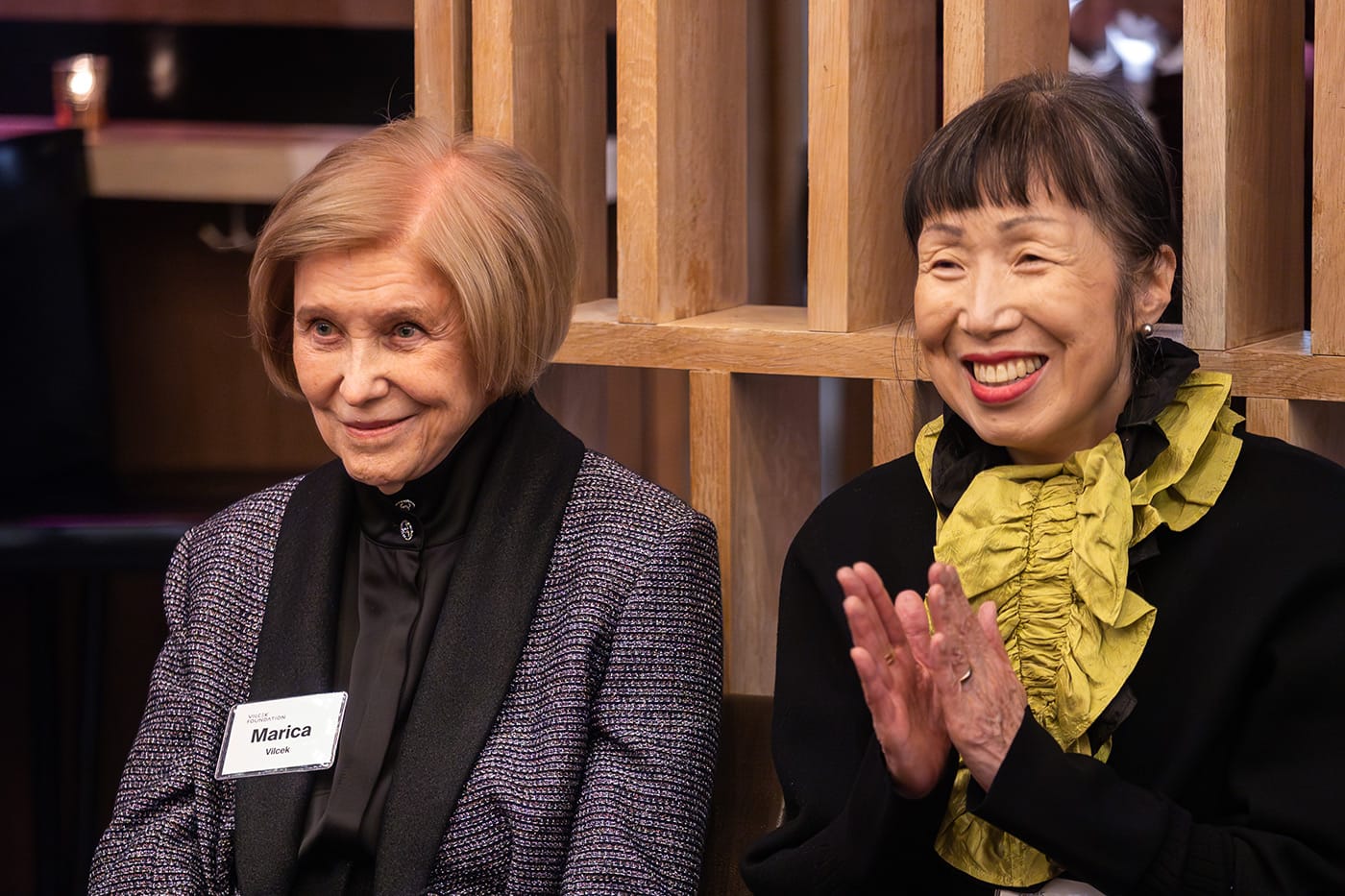 Jung Lee Sanders smiling and clapping next to Marica Vilcek