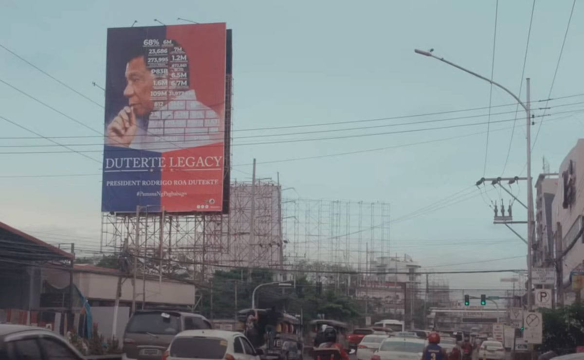 A street in the Philippines with a billboard with former president Rodrigo Duterte pictured.