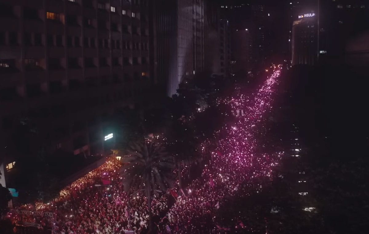 An aerial view at night showing of a crowd of people with pink lights that shine through the darkness.