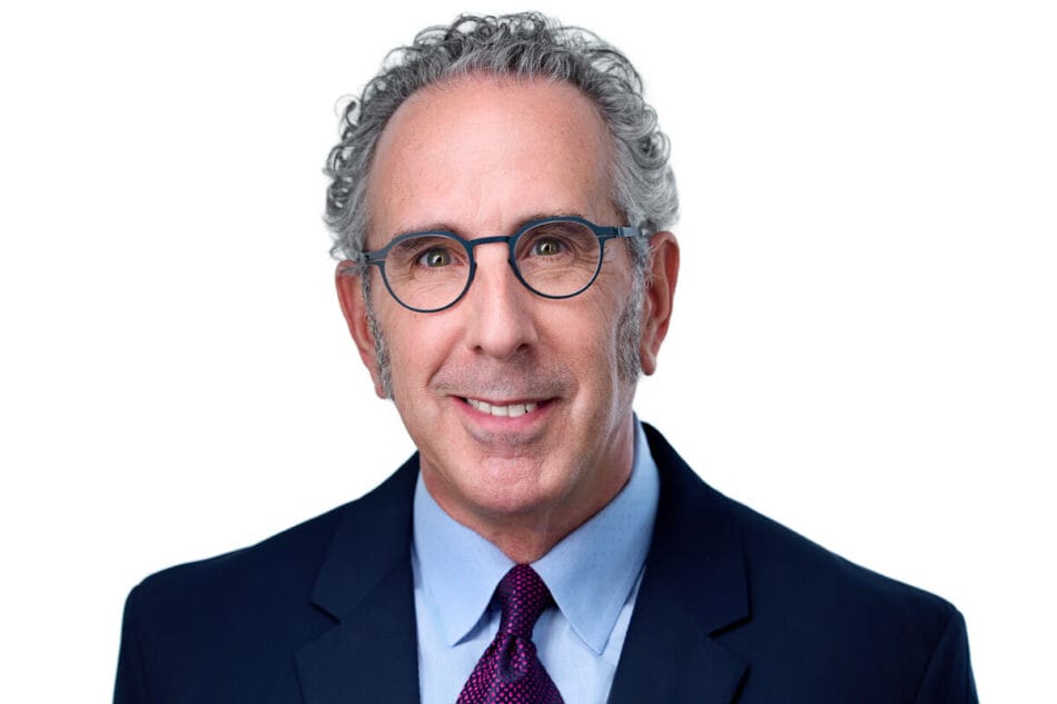 A portrait of Andrew Sanders with glasses, a tie, and a blazer.