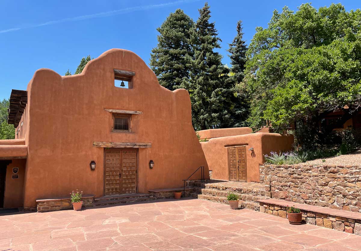 A large stucco building amongst trees.