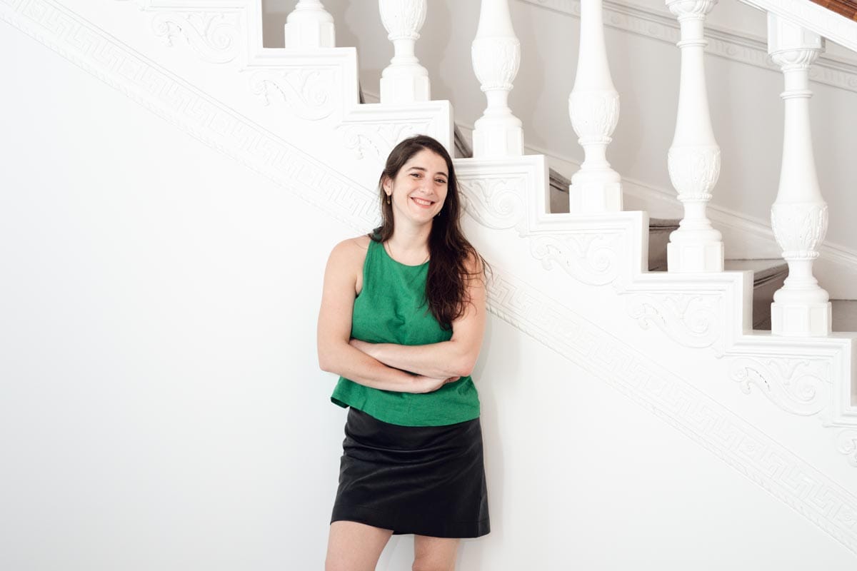 Aimé standing in front of a white staircase, smiling with her arms folded.