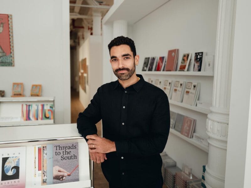 Bernardo leans on a book display case in the lobby of an art gallery.