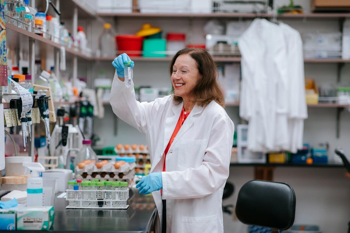 Marianne smiles as she examines a test tube sample in her lab.