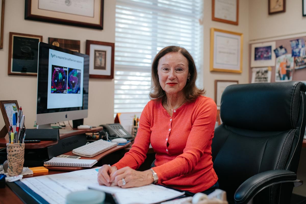 Marianne sitting at her desk in her office in front of a computer with scans visible.