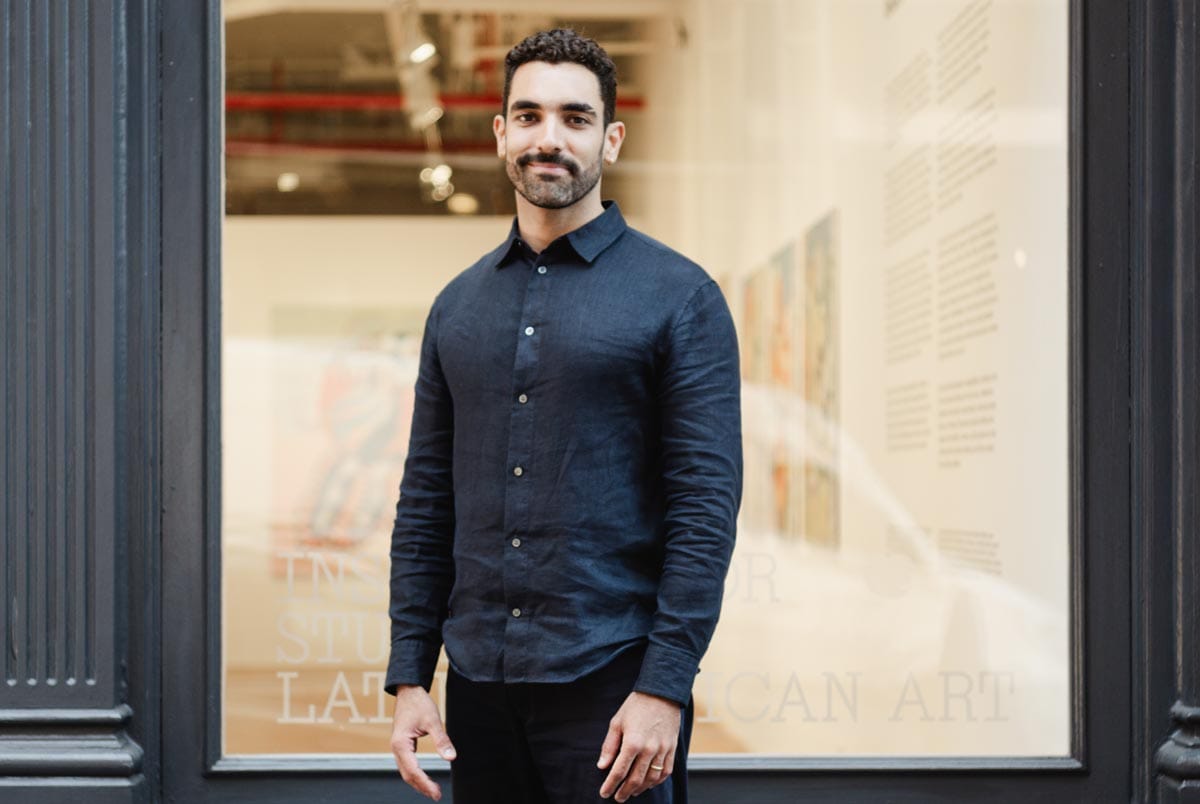 Bernardo standing in front of a large window with an art gallery visible inside.