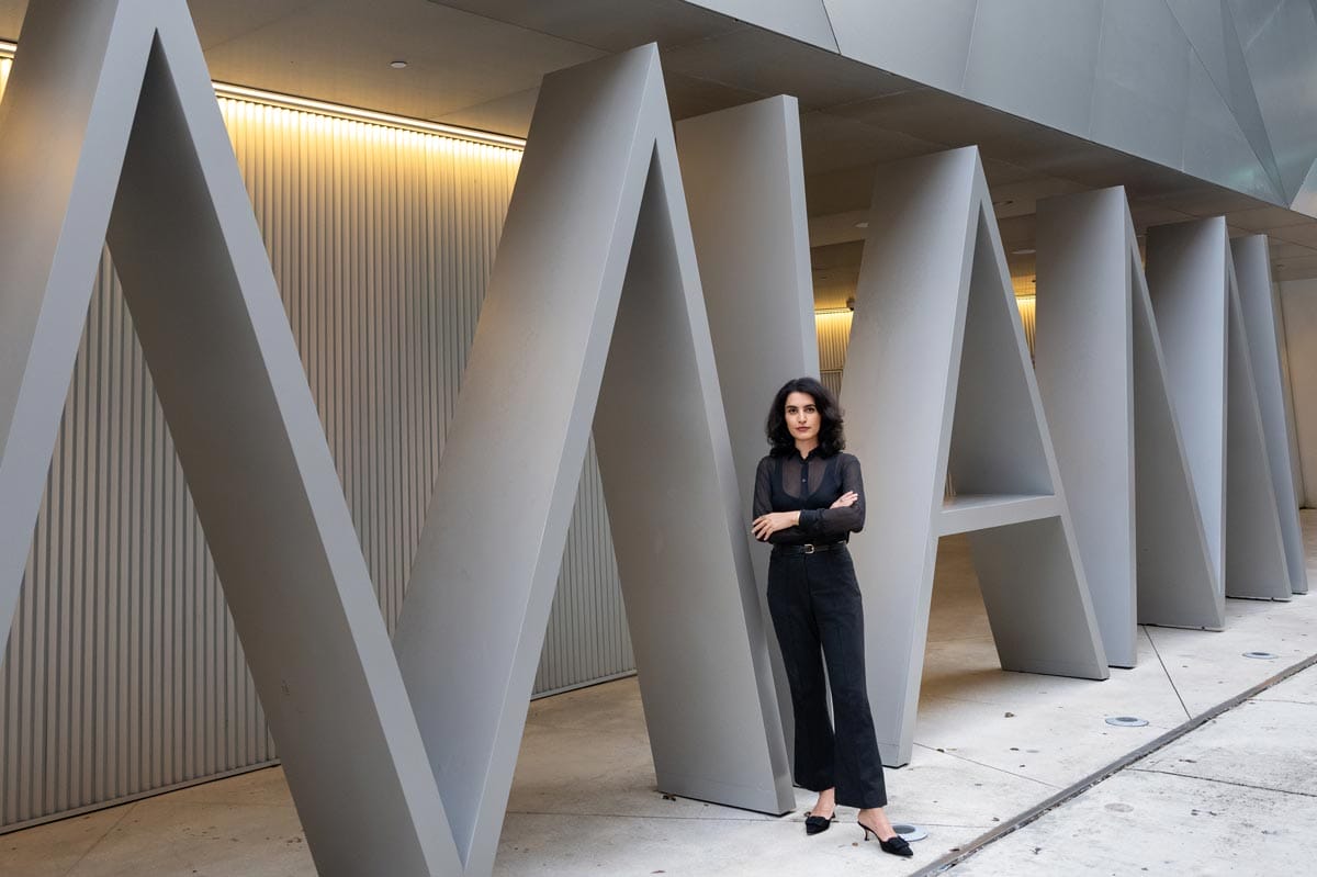 Donna standing in front of a large architectural feature with the word 