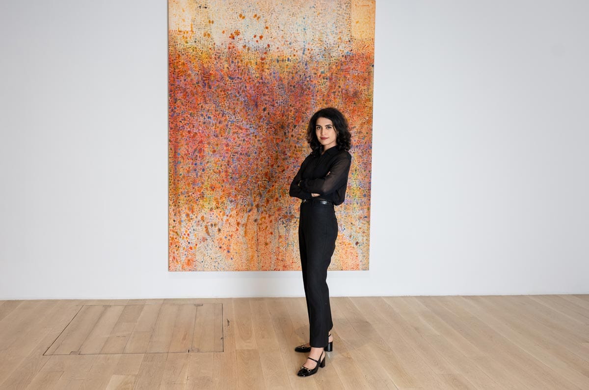 Donna posing in front of a large orange painting by Tomm El-Saieh.