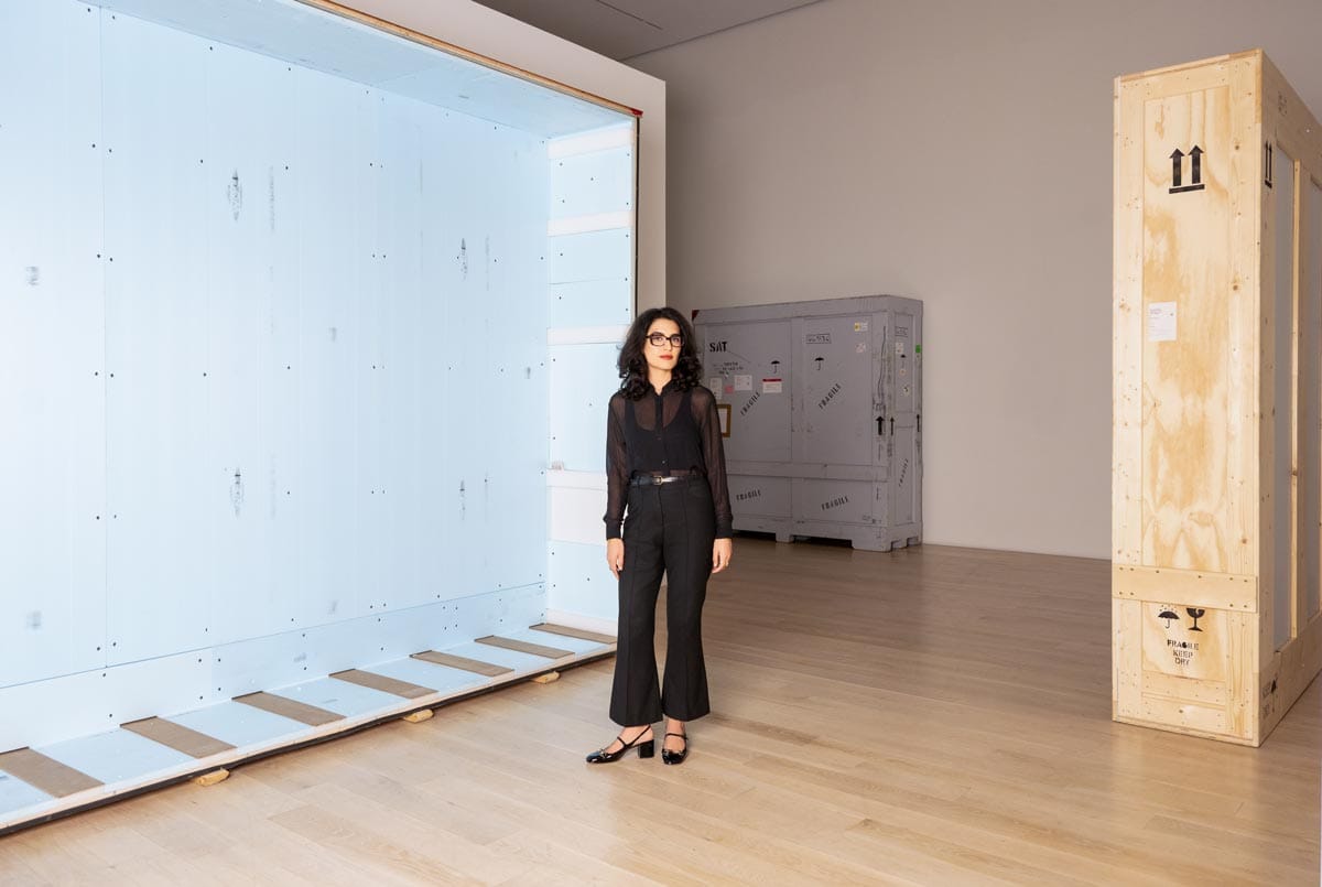 Donna stands in front of large empty wooden crates.