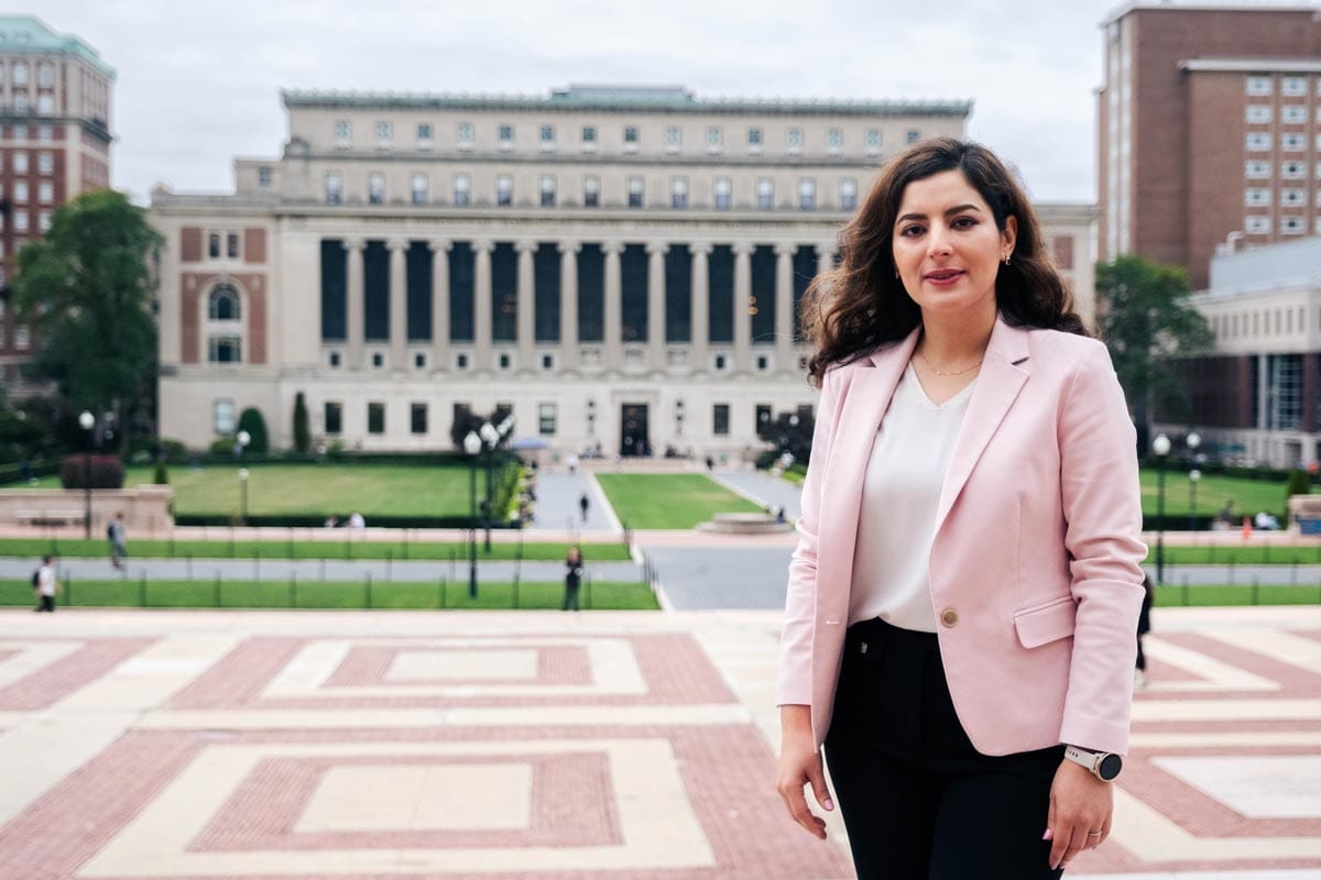 Elham standing on the steps of the Columbia University library with the campus gardens, grounds and buildings visible behind her.