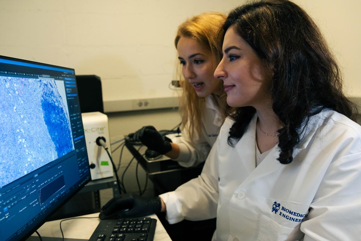 Elham and a lab member examining microscope imagery.