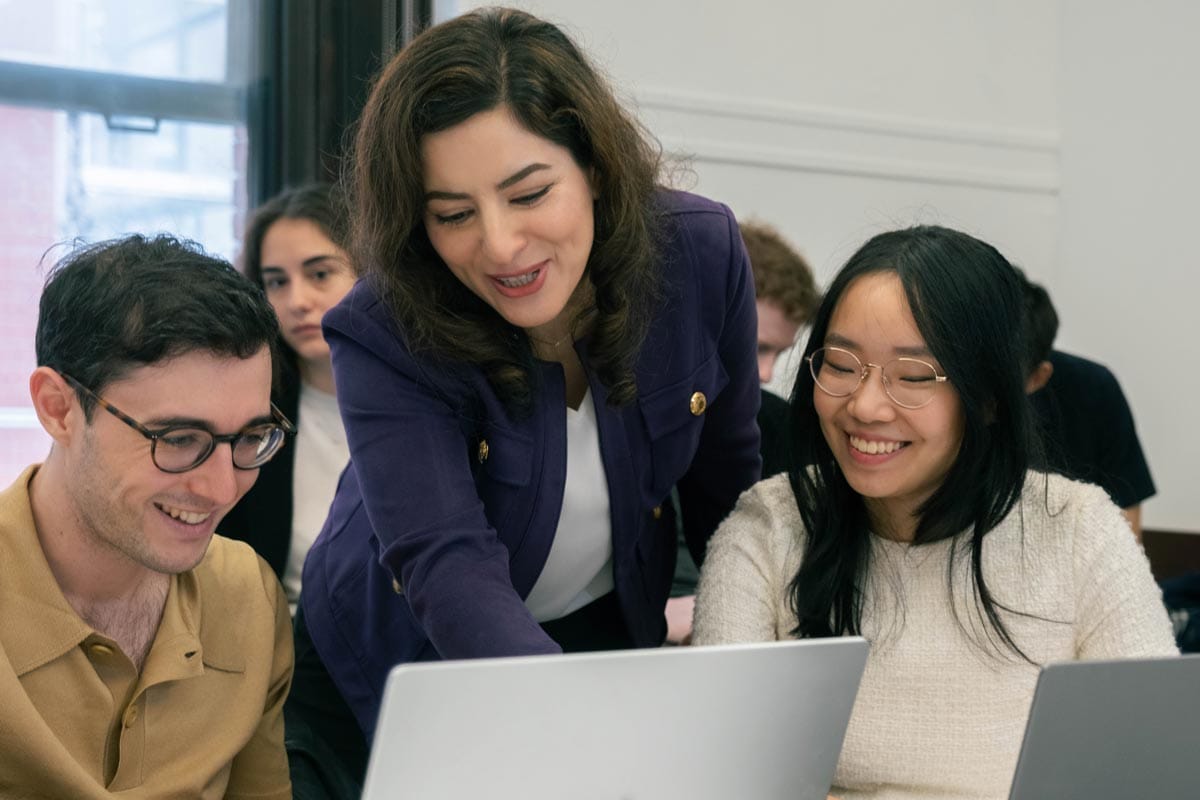 Elham talks with two of her lab members as they work from a laptop.