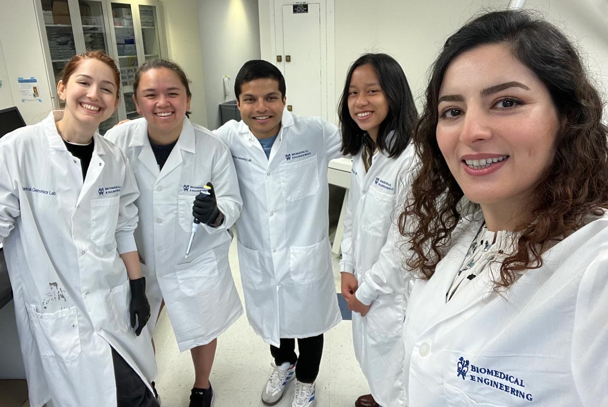 Elham (far right) pictured with four of her lab members - all wearing white lab coats.