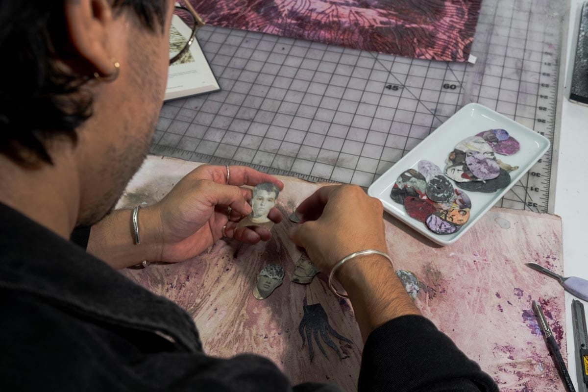 Felipe working with small cut-outs depicting human heads.