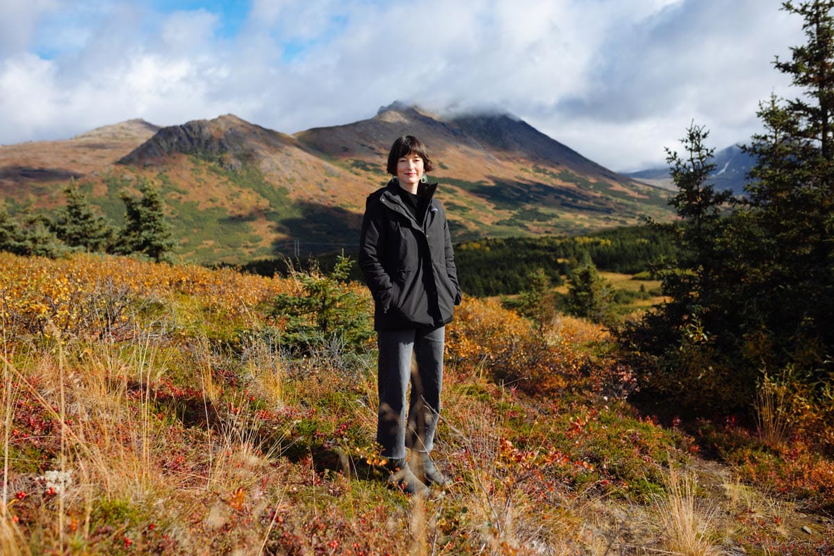 A wide shot of Francesca standing out in nature in Alaska.