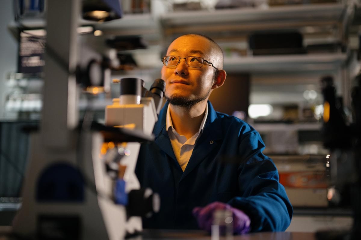 Guosong looking up and to the left as he prepares to use a microscope.