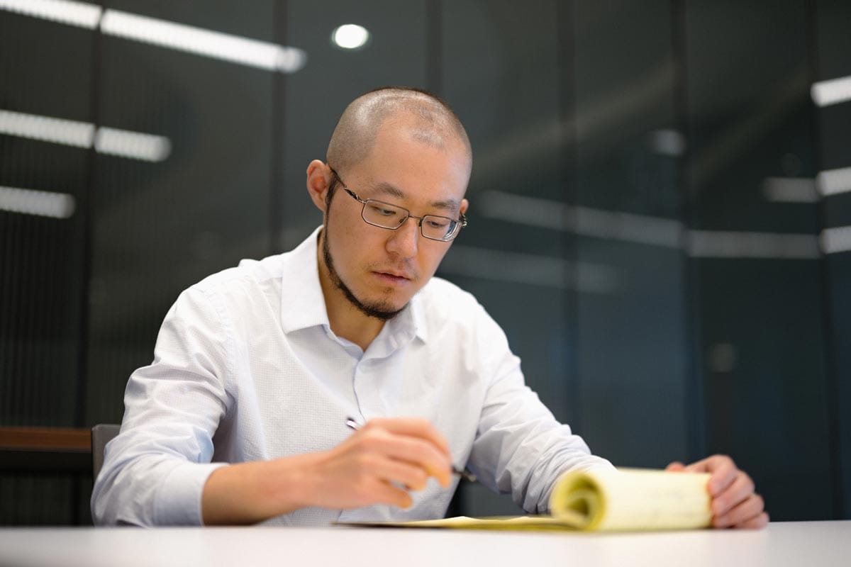 Guosong looking intently at a yellow note pad.