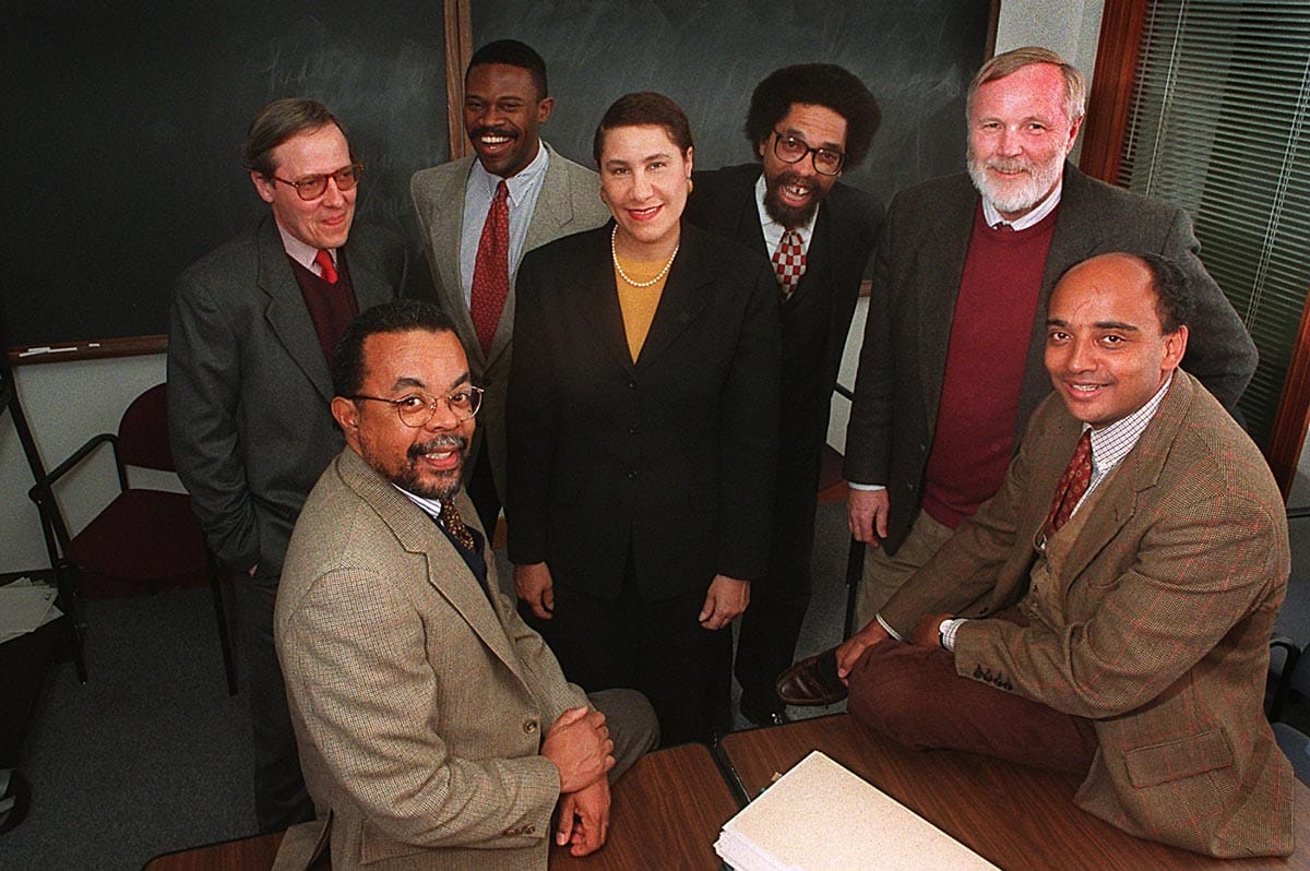 Seven people pose in a classroom in front of a chalkboard: (Front left) Henry Louis Gates, Jr., (left to right) Werner Sollops, J. Lorand Matory, Evelyn Higgenbotham, Cornel West, John F. Kain, and K. Anthony Appiah. 