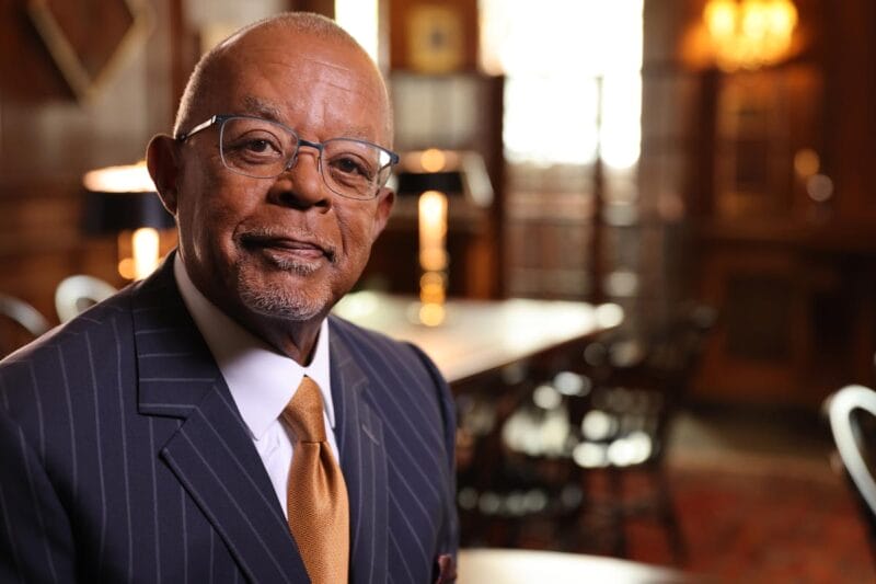 A portrait of Henry Louis Gates Jr. with a conference room out of focus in the background.