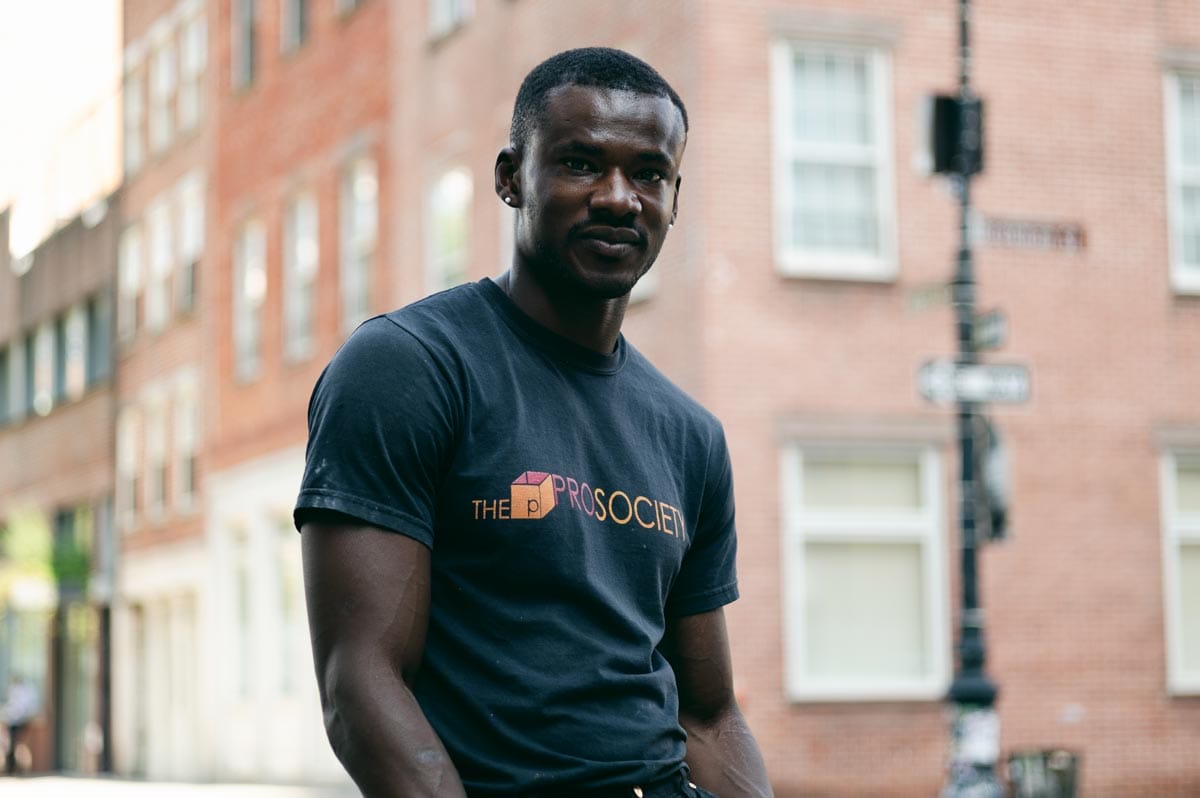 Jeffrey standing on the street in the Financial District in NYC with a red brick building behind him. 