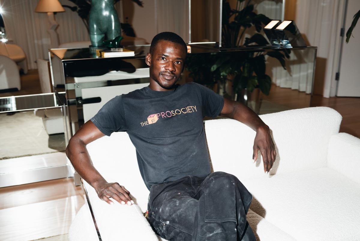 Jeffrey sitting on a white couch with plants and sculptures visible behind him. 