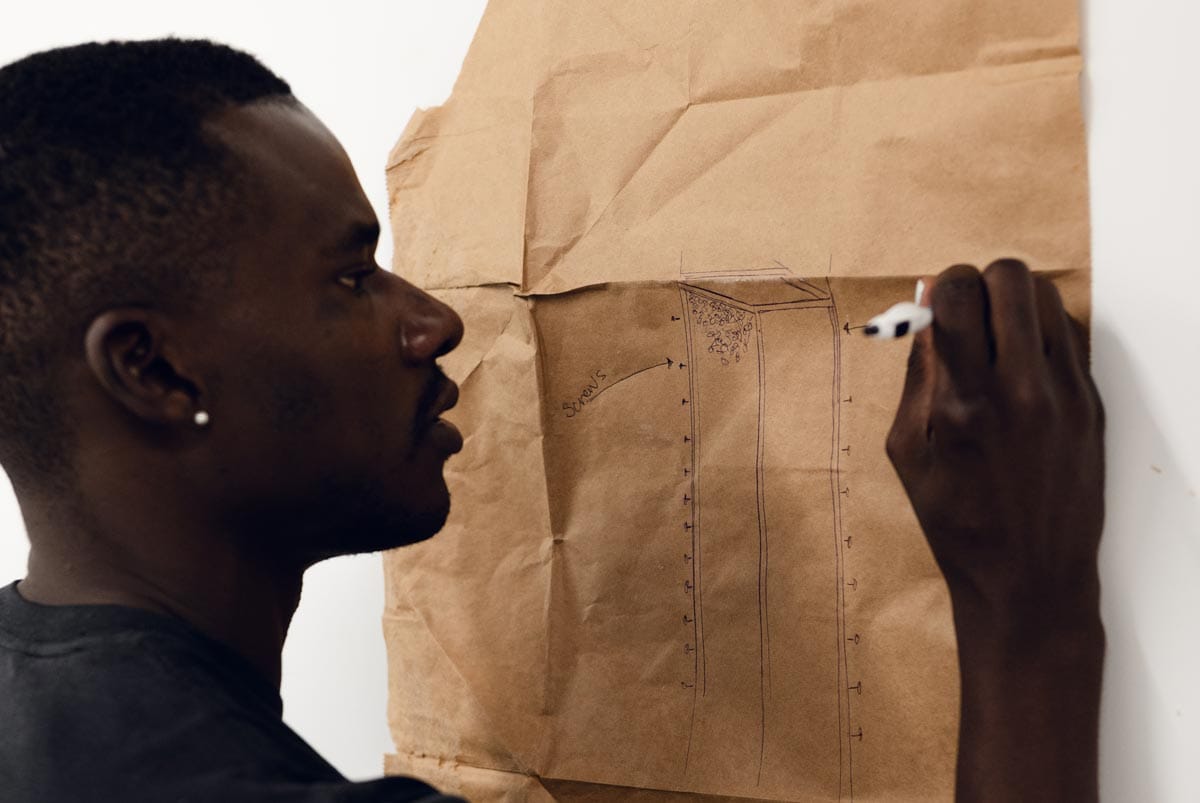 Jeffrey draws on a piece of craft paper pinned to the wall of his studio.