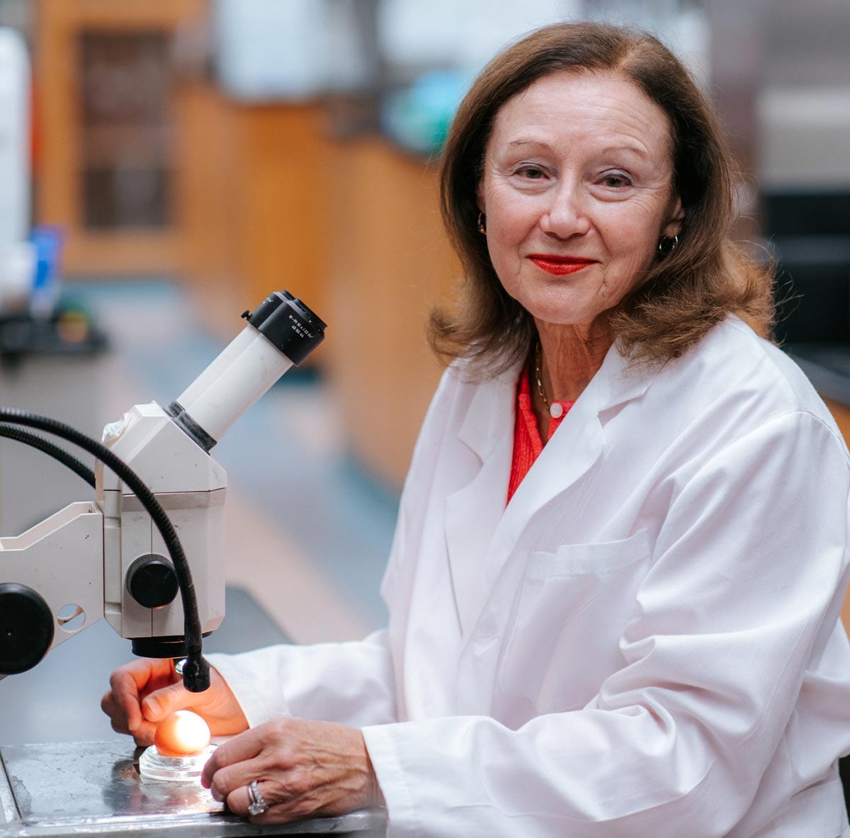 Marianne sitting in front of a microscope in her lab.