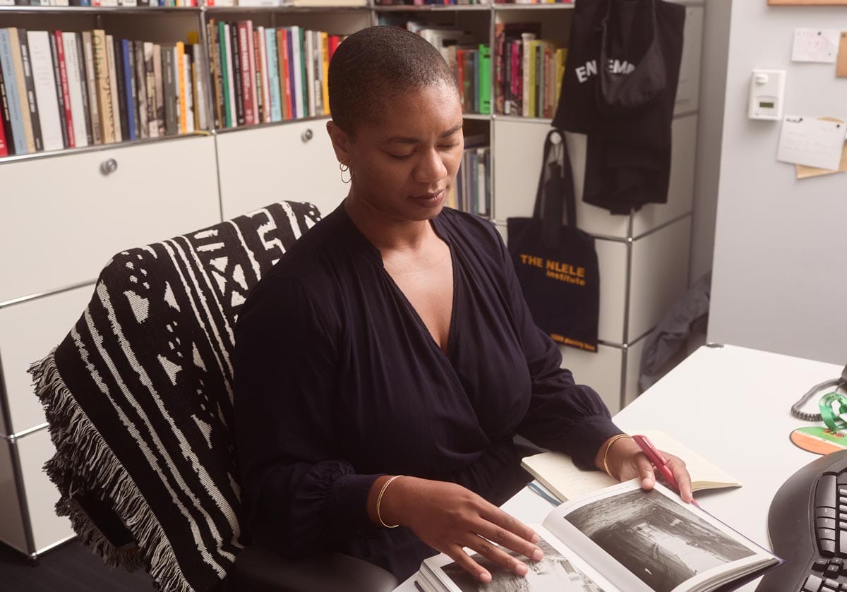 Oluremi working at a desk with a bookshelf and storage drawers behind her.