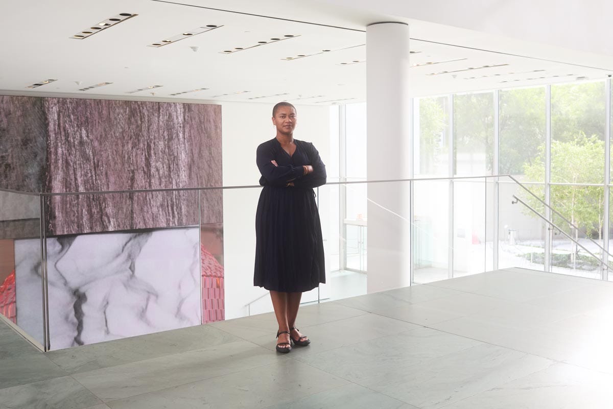 Oluremi standing in the gallery space at the MoMA with a projection in the background behind her. 