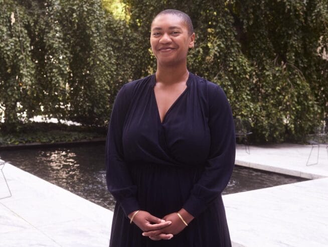 Oluremi standing in the Sculpture Garden at the MoMA with green trees visible behind her.