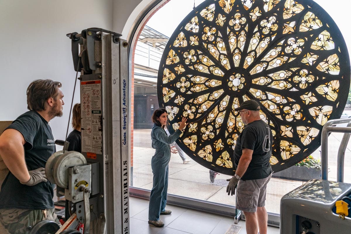 Selva and her team deinstalling an exhibition with a large ornate wheel.