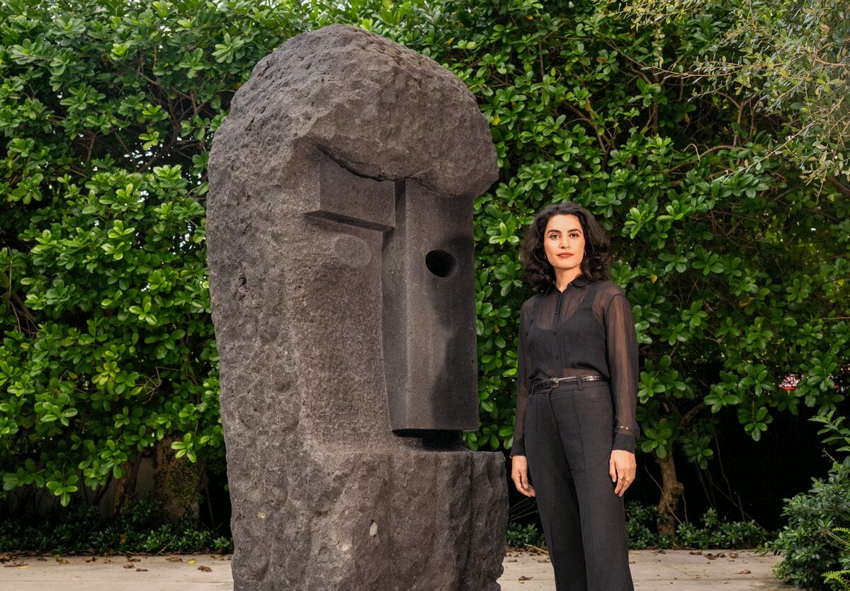 Donna stands right of a large stone sculpture with geometric facial features.