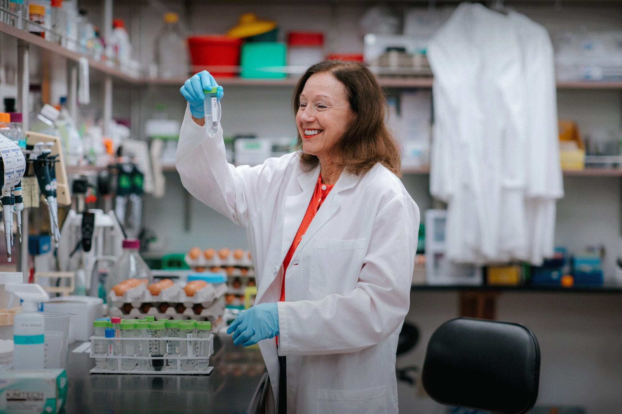 Marianne smiles as she examines a test tube sample in her lab.