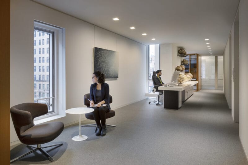 Reception area with person sitting in chair looking out a window.