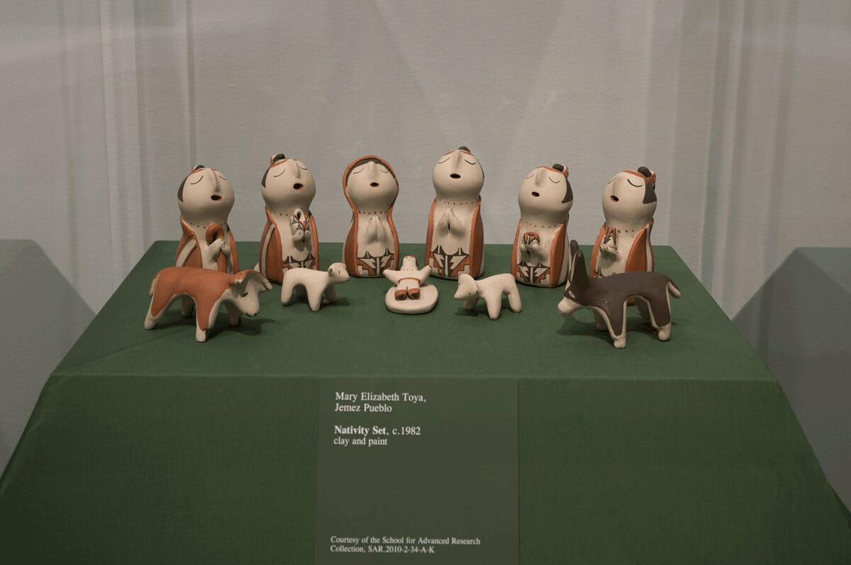 An eleven piece clay nativity set decorated with red and black designs.