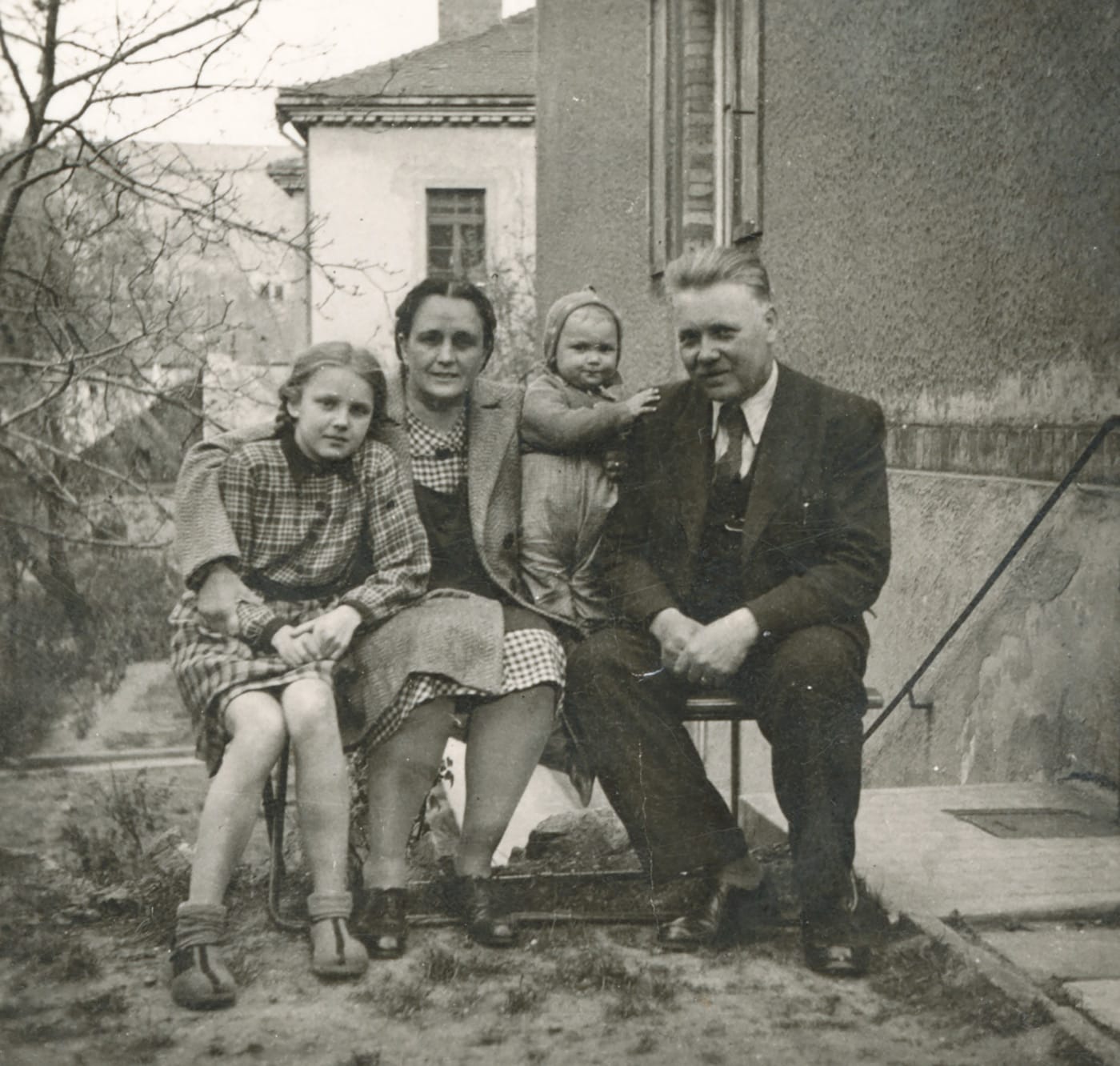 A photograph of a family sitting in their backyard garden in the 1940s.