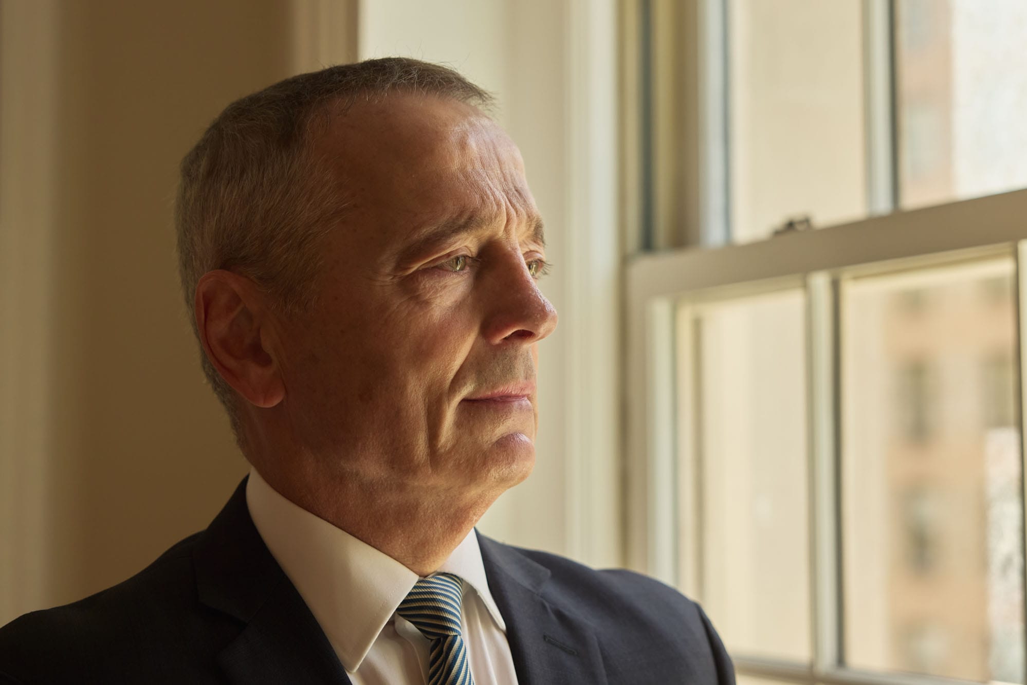 Portait of Matthew Bogdanos looking off to the side towards a window in his office